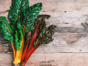 Multi-colored swiss chard on wooden background. Top view. Copy space. Zero waste, organic vegetables concept. Vegan and vegetarian diet food. Borecole Cavolo Nano Green Curled semi
