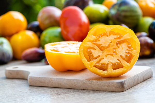 table with a cutting board with sliced tomatoes and different colored tomatoes in the background Pomodoro Azoychka